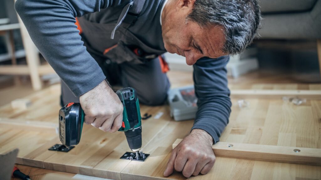 image showing an assembly technician using a drill on a piece of wood