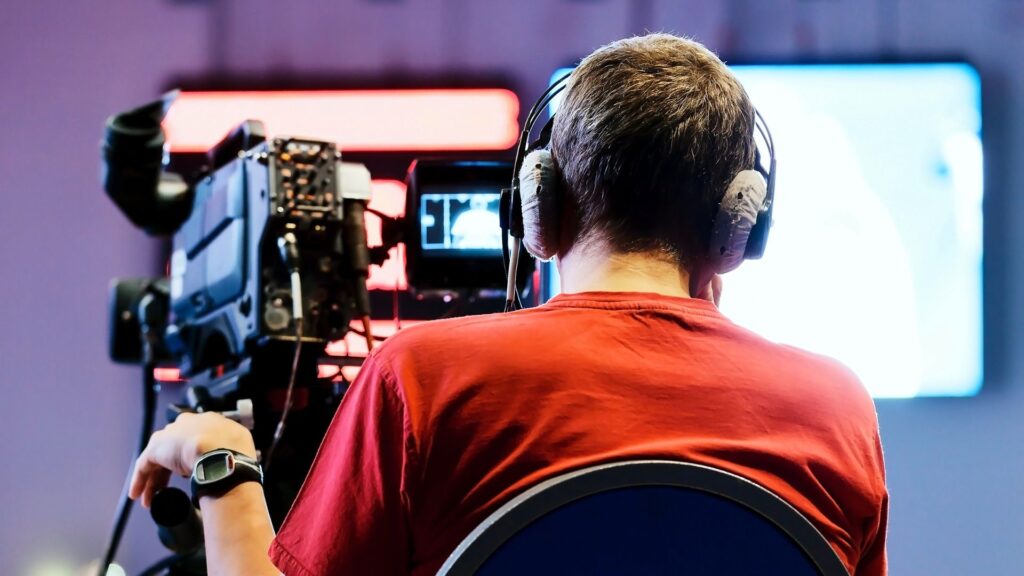 image showing a camera operator standing behind a camera