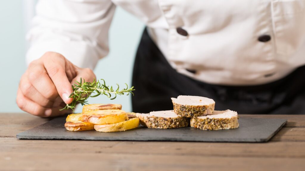 image showing a head chef placing a garnish on a food