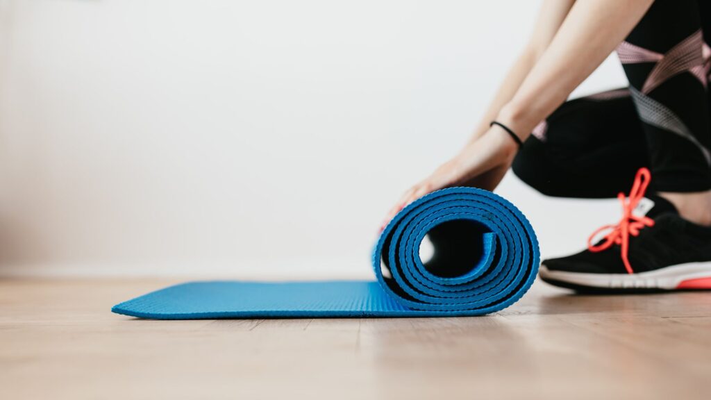 image showing a pilates instructor rolling up a mat