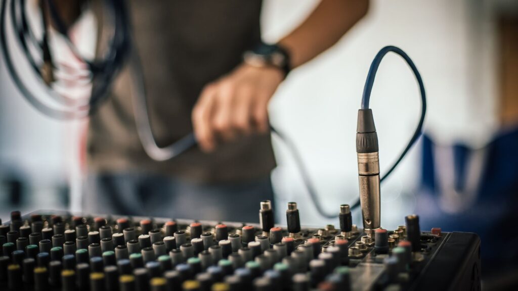 image showing a sound technician hooking cords up to an audio receiver
