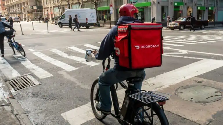 image showing a doordash courier on a bike - header for does doordash hire felons post