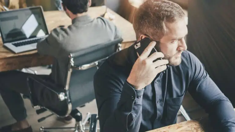 image of a man sitting at a desk and talking on the phone - for account manager resume example post on myjobsearch.com