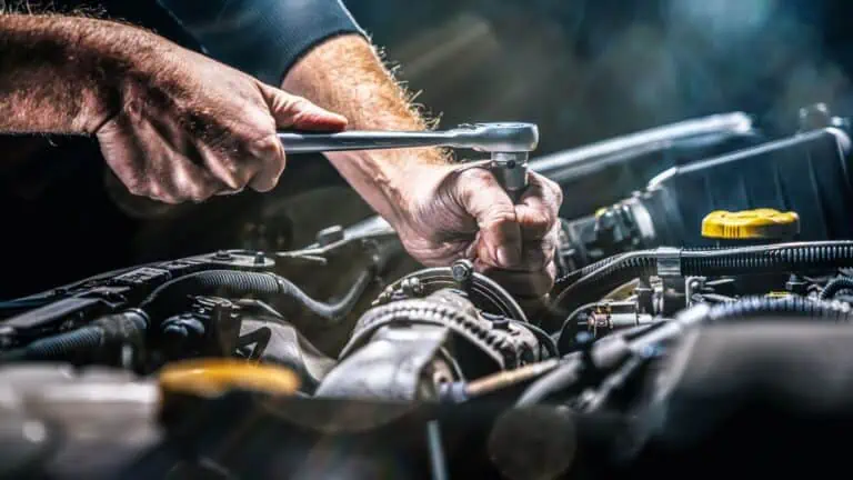 image of a mechanic turning a wrench on a vehicle engine - header graphic for mechanic resume post on myjobsearch.com